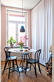 Dining area with round table, black chairs and tulips