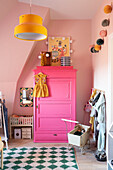 Children's room with pink wardrobe, yellow lamp, pink walls and toys