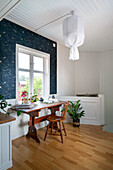 Wooden desk in front of window and dark patterned wallpaper