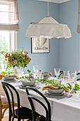 Set dining table with tablecloth and vintage lamp in dining room with light blue painted walls