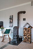 Wood-burning stove with firewood holder and modern chair in the living room