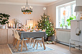 Festlich gedeckter Esstisch und Weihnachtsbaum im hellen Wohnzimmer