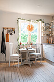 Bright dining area with white furniture set and ivy decorations on the window