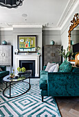 Velvet sofas, carpet with geometric pattern and classic fireplace in the living room