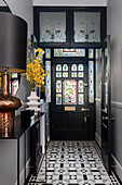 Door with stained glass, marble console and decorative tiled floor in the entrance area