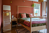 Bedroom with terracotta wall, wooden bed and patterned carpet