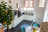 Bright kitchen with citrus tree and colourful chairs at the dining table