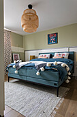 Bedroom with green wall, rattan ceiling lamp and blue bed