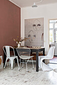 Dining area with various chairs and large mural, rust-coloured wall