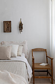 Bedroom in natural tones with wooden chair and light-coloured bed linen