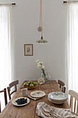 Wooden table with rustic crockery and floral decorations in a neutral dining room