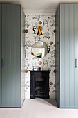 Fireplace in front of patterned wallpaper between two wardrobes