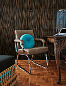 Retro-Bürostuhl mit türkisfarbenem Kissen vor verziertem Holzschreibtisch