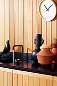 Küchenzeile mit Holzpaneele, schwarzer Arbeitsplatte und Dekorationsobjekten