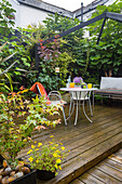 Gemütliche Terrassenecke mit Holzdielen und üppiger Bepflanzung im Sommer