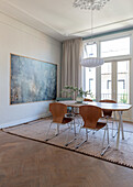 Essbereich mit Holztisch, braunen Stühlen und modernem Kunstwerk