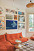 Living room with orange sofa and picture wall