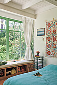 Helles Schlafzimmer mit großen Fenstern und Blick ins Grüne