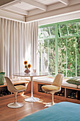 Heller Sitzbereich, grüne Fensterrahmen und Gartenblick