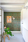 Bright room with patterned wallpaper, wooden stool and houseplant