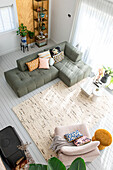 Helles loftartiges Wohnzimmer mit L-förmigem Sofa, bunten Kissen und texturiertem Teppich