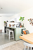 Modern kitchen with mint green tiled island with dining area in the foreground