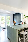 Kitchen with mint green tiled island and bar stools