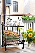 Balkon mit Sonnenblumen und dekorativem Servierwagen mit Kissen