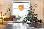 Wohnzimmer mit Weihnachtsbaum und Sessel vor Fenster