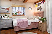 Gemütliches Schlafzimmer mit rosafarbenem Bett und Terrakottafliesen