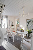 Brightly decorated dining area with white chandelier and wooden staircase