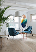 Bright living room with two blue armchairs and arc lamp
