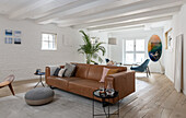 Bright living room with leather couch, wooden floor and wall decoration