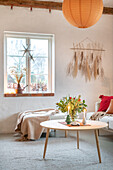 Brightly decorated living room with round wooden coffee table and dried flowers on the wall