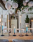 Wooden table with blue candles and hanging paper decorations in dining room