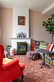 Vintage armchair, sofa with pillows and wood-burning stove in living room