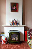 Wood-burning stove, candles and porcelain figurines on mantelpiece in living room