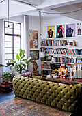 View of green velvet sofa and wall of books in loft living room
