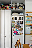 Weißer Schrank mit bunten Vorratsdosen und Schalen und  Kühlschrank mit bunten Postkarten