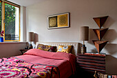 Double bed with colourful textiles and wooden decorations in the bedroom