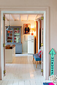 Blick durch eine offene Tür in eine helle Landhausküche mit Holzmöbeln