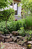 Creative garden design with rust sculpture and natural stone wall