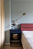 Bedroom with dark blue bedside table, modern table lamp and decorative vase