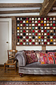 Grey velvet sofa with colourful cushions in front of shelf with colourful spools of yarn