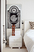 Bedroom with mural, white bedside table and wall lamp