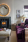 Living room with fireplace, round illuminated mirror and purple sofa