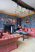 Living room with fireplace, patterned wallpaper and red upholstered furniture