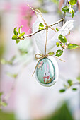 Hand-painted Easter egg with bunny motif on spring branch
