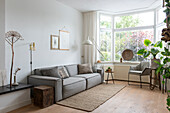 Brightly furnished living room with grey sofa and large bay windows
