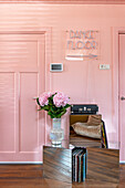 Pink wall with neon light lettering and hydrangea in vase on mirrored table